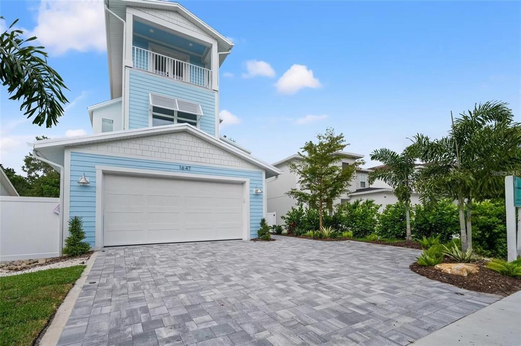 A light blue two-story house with a white garage door and a paved driveway — 1647 SIESTA DRIVE, SARASOTA, FL