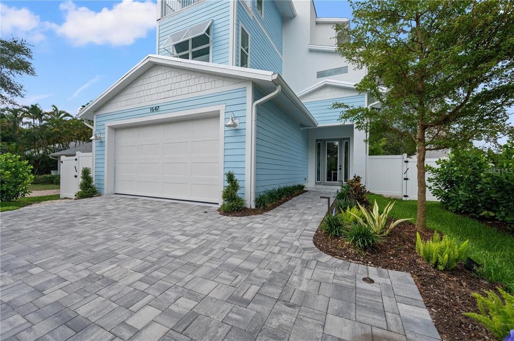 A light blue two-story house features a paved driveway, a garage, and a front walkway — 1647 SIESTA DRIVE, SARASOTA, FL