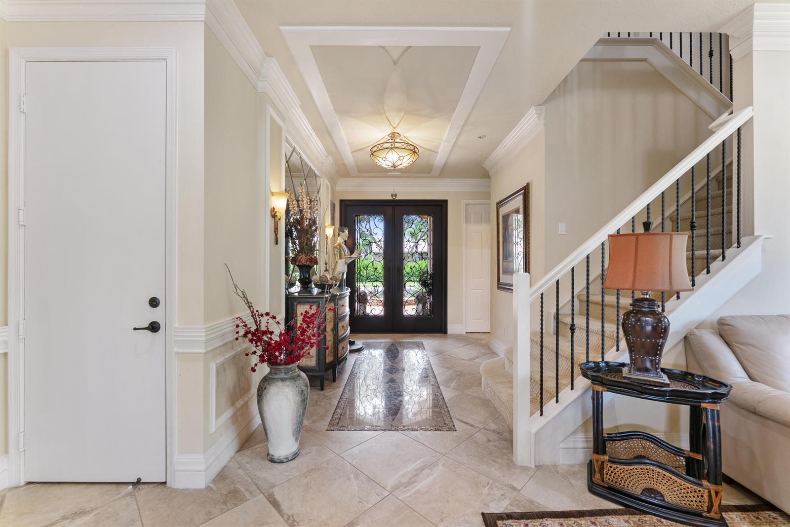 A bright foyer features a tiled floor, a grand staircase, and double glass-paneled entry doors — 11790 Foxbriar Lake Trail, Boynton Beach FL 33473, BOYNTON BEACH, FL