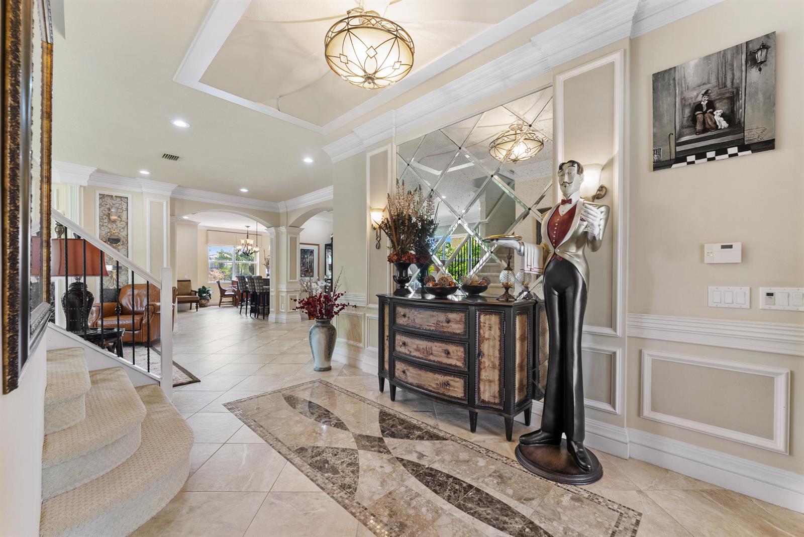 A grand foyer features a tiled floor, a decorative butler statue, and a mirrored wall — 11790 Foxbriar Lake Trail, Boynton Beach FL 33473, BOYNTON BEACH, FL