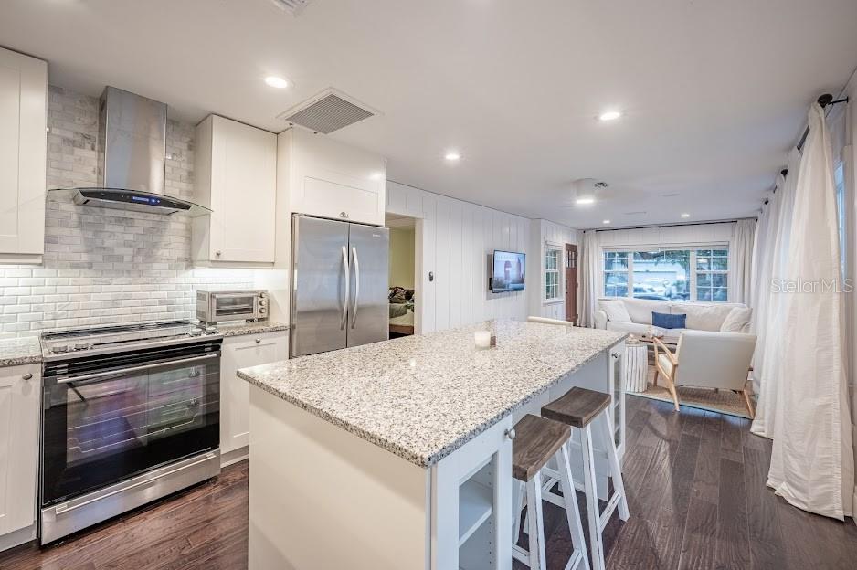 A kitchen with white cabinets, granite countertops, and an island overlooks a living room area — 1837 WORRINGTON STREET, SARASOTA, FL