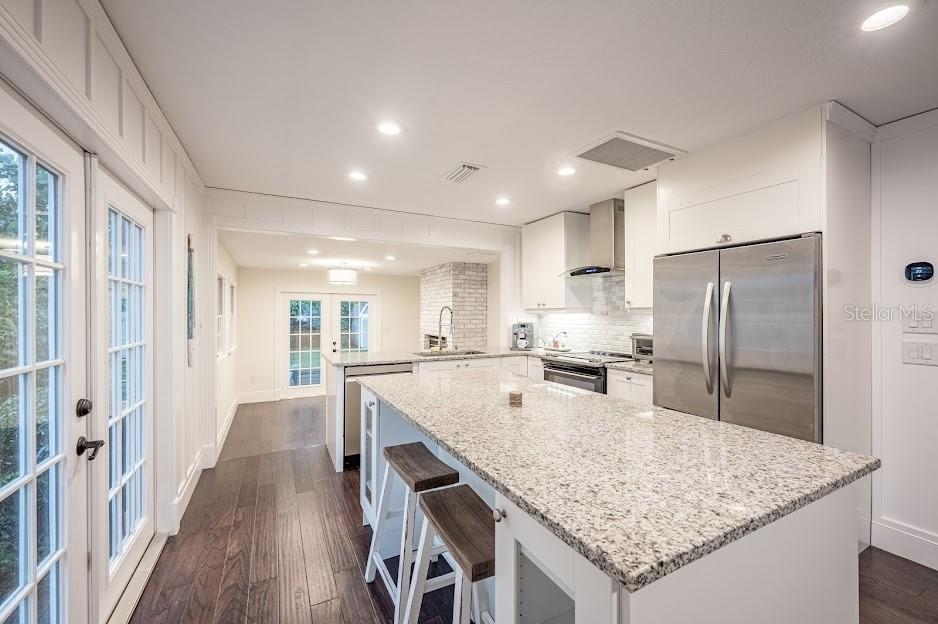 A modern kitchen features white cabinetry, granite countertops, a central island, and dark wood flooring — 1837 WORRINGTON STREET, SARASOTA, FL