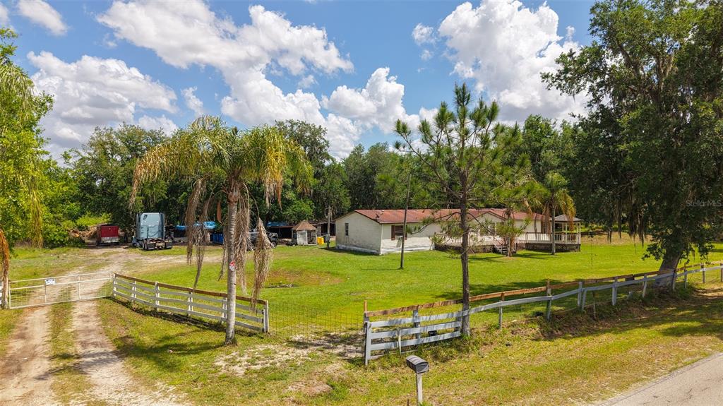 An exterior view of a single-story house with a fenced yard and a dirt driveway — 3604 CORK ROAD, PLANT CITY, FL