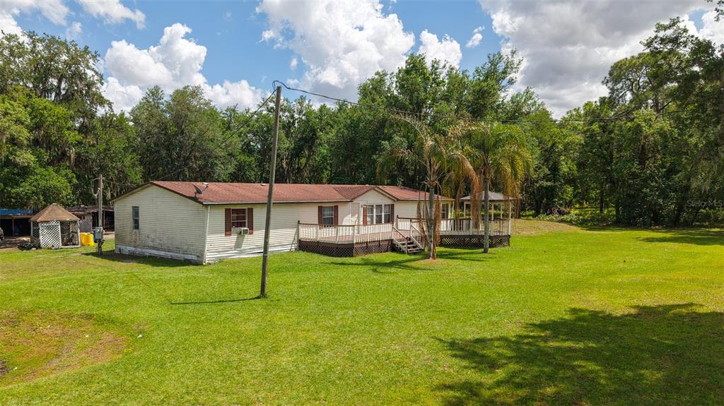 A single-story manufactured home with a wooden deck sits on a large, grassy lot — 3604 CORK ROAD, PLANT CITY, FL