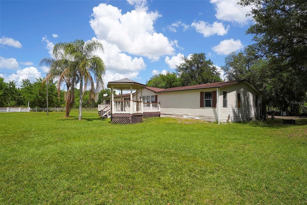 A single-story house with light siding features a wooden deck and a gazebo attached — 3604 CORK ROAD, PLANT CITY, FL