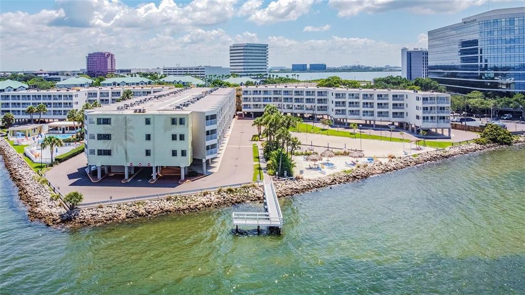 An aerial view shows a multi-story apartment complex situated on a waterfront point with a dock — 2506 N ROCKY POINT DRIVE UNIT 305, TAMPA, FL