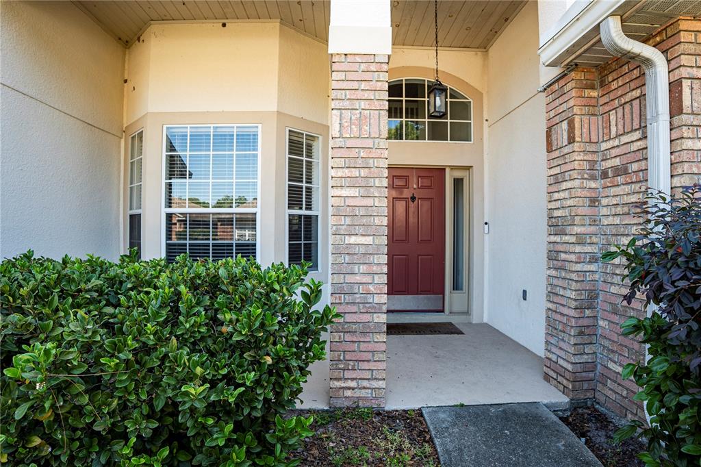 The exterior view shows a red front door, brick columns, and a bay window — 1400 BENT OAKS BOULEVARD, DELAND, FL