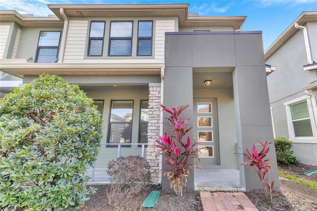 The exterior of a two-story townhouse features a stone-accented porch and a modern front door — 2274 CENTERRA LOOP, KISSIMMEE, FL