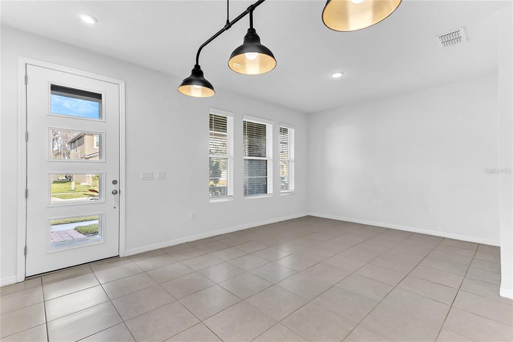 A bright dining area features light tile flooring, white walls, three windows, and pendant lighting — 2274 CENTERRA LOOP, KISSIMMEE, FL