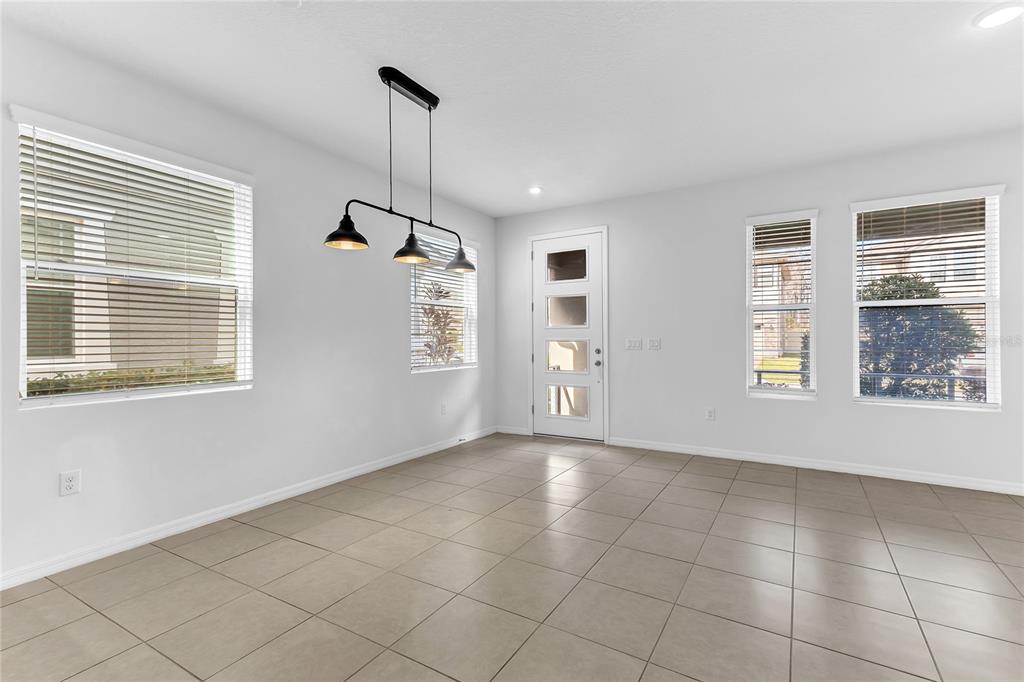A bright dining area features light tile flooring, a modern pendant light, and white walls — 2274 CENTERRA LOOP, KISSIMMEE, FL