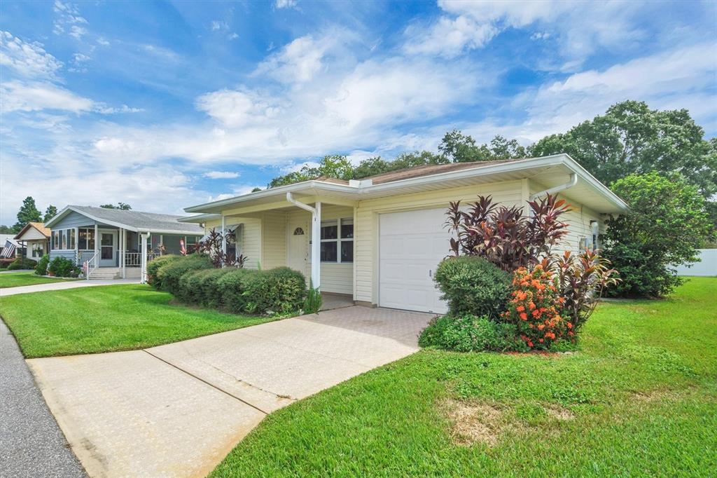 A single-story house with light yellow siding, a concrete driveway, and a one-car garage — 4938 COLONNADES CIRCLE E, LAKELAND, FL