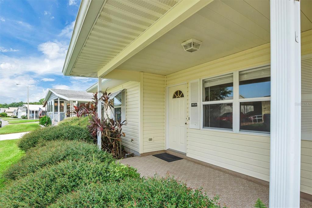 A covered front porch with a white door and siding on a suburban home — 4938 COLONNADES CIRCLE E, LAKELAND, FL