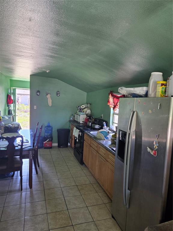 A kitchen with green walls, wood cabinets, stainless steel appliances, and a dining area — 1545 WASHINGTON STREET, WAUCHULA, FL