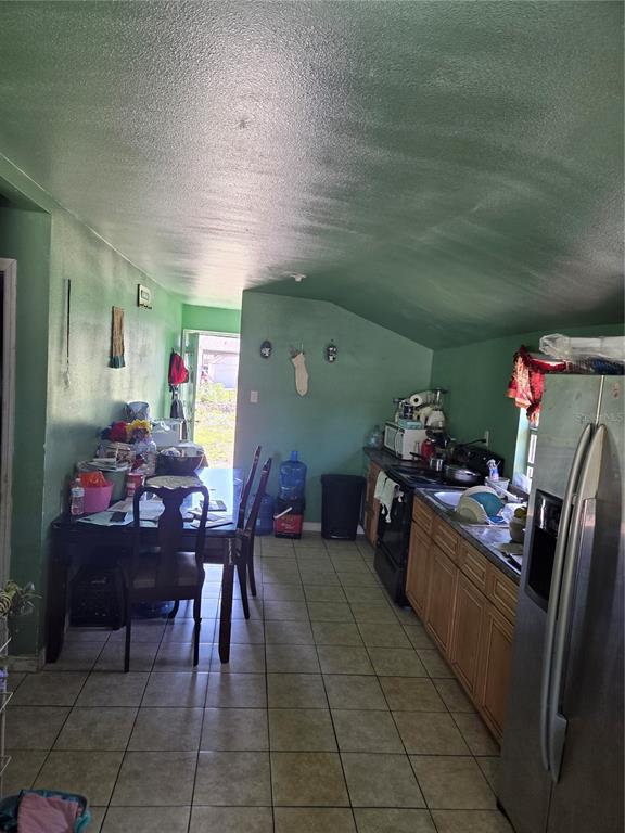 A kitchen with green walls, light wood cabinets, tile flooring, and an adjacent dining area — 1545 WASHINGTON STREET, WAUCHULA, FL