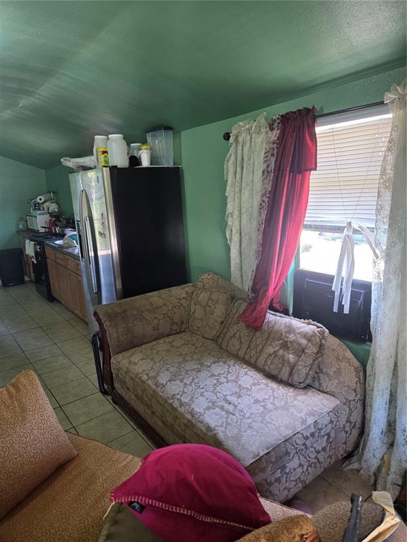 A living area with a patterned sofa, green walls, and an adjacent kitchen with appliances — 1545 WASHINGTON STREET, WAUCHULA, FL
