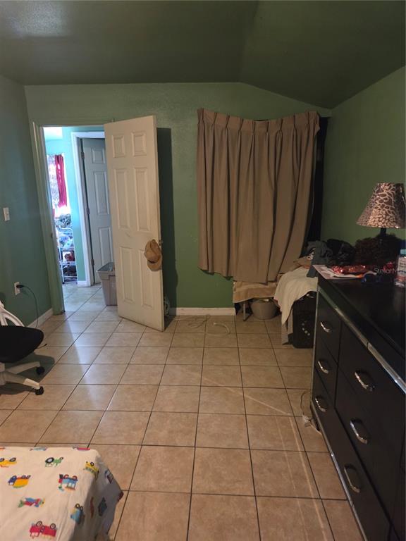 A bedroom with green walls, tile flooring, a dark dresser, and an open doorway — 1545 WASHINGTON STREET, WAUCHULA, FL