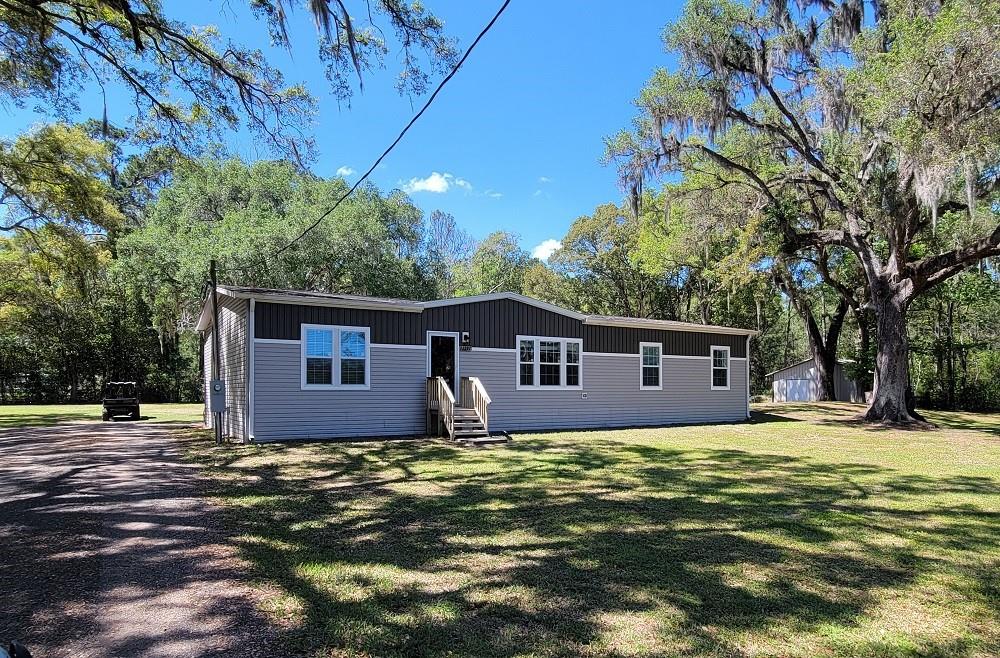 A single-story manufactured home with grey siding and a dark brown upper trim exterior — 22397 MONDON HILL ROAD, BROOKSVILLE, FL
