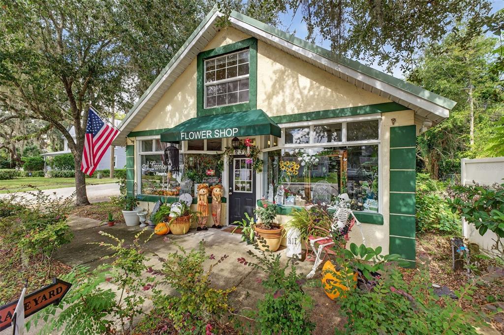 A small, yellow, single-story flower shop with green trim and a front porch — 237 E PLYMOUTH AVENUE, DELAND, FL