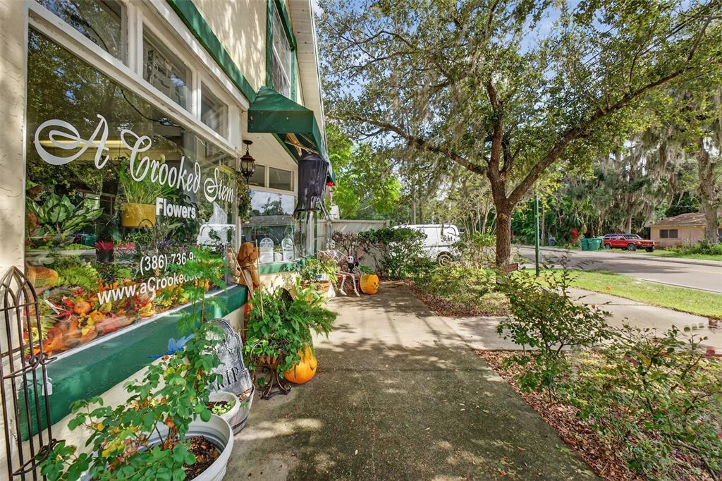 The exterior of a flower shop features a sidewalk, storefront window, and Halloween decorations — 237 E PLYMOUTH AVENUE, DELAND, FL