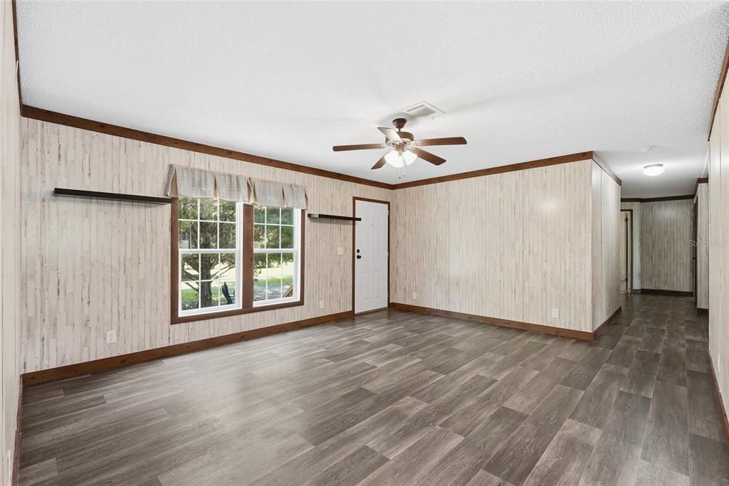 A living room features wood-look flooring, light-colored vertical paneling, a ceiling fan, and a window — 291 SW LEGION DRIVE, LAKE CITY, FL