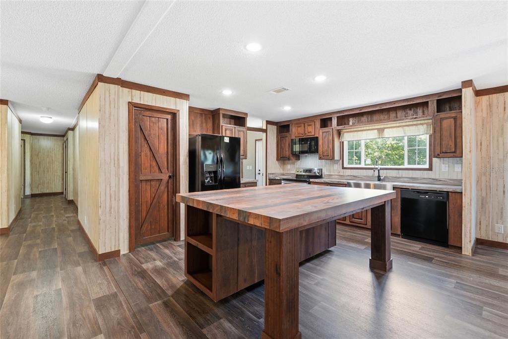 A kitchen features a large wooden island, dark wood cabinetry, and light wood-paneled walls — 291 SW LEGION DRIVE, LAKE CITY, FL