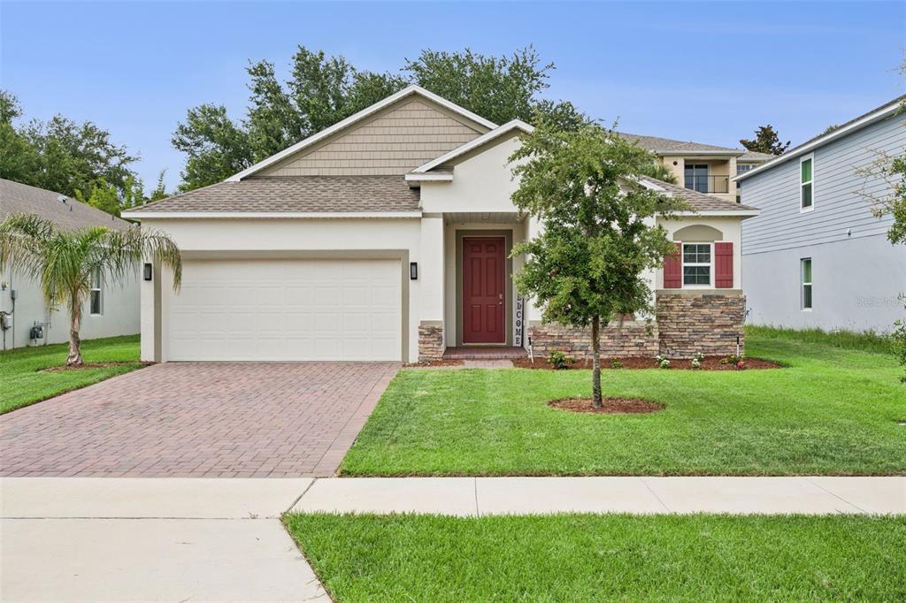 A single-story house with a brick driveway, red front door, and stone facade accents — 1029 BRADFORD RIDGE DRIVE, LEESBURG, FL