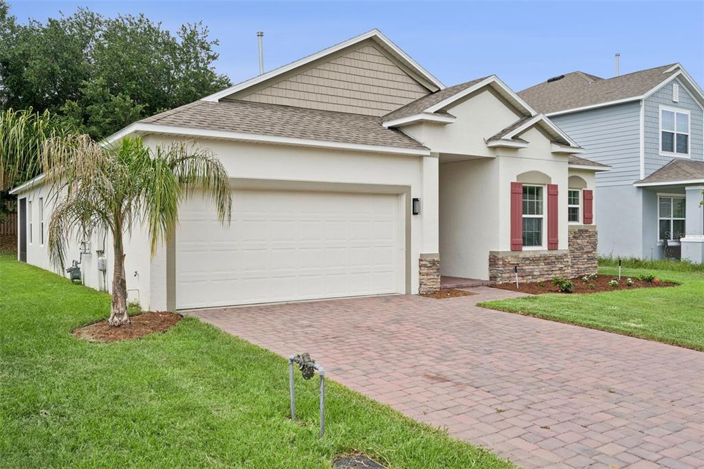 A single-story house with a two-car garage, stone accents, and a brick paver driveway — 1029 BRADFORD RIDGE DRIVE, LEESBURG, FL