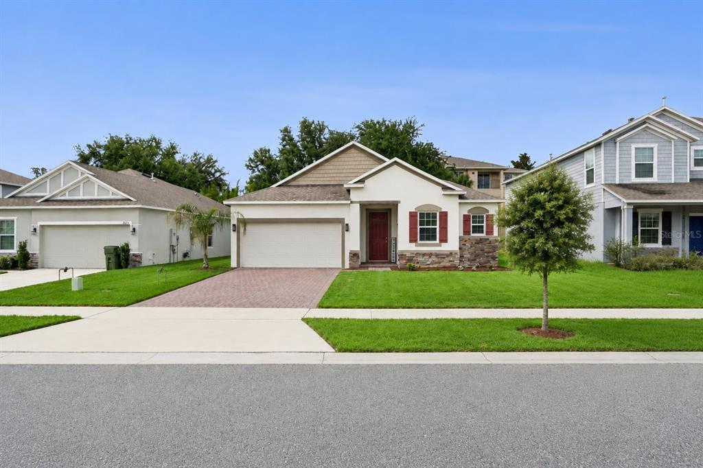 A single-story suburban house with a two-car garage, stone accents, and a paved driveway — 1029 BRADFORD RIDGE DRIVE, LEESBURG, FL