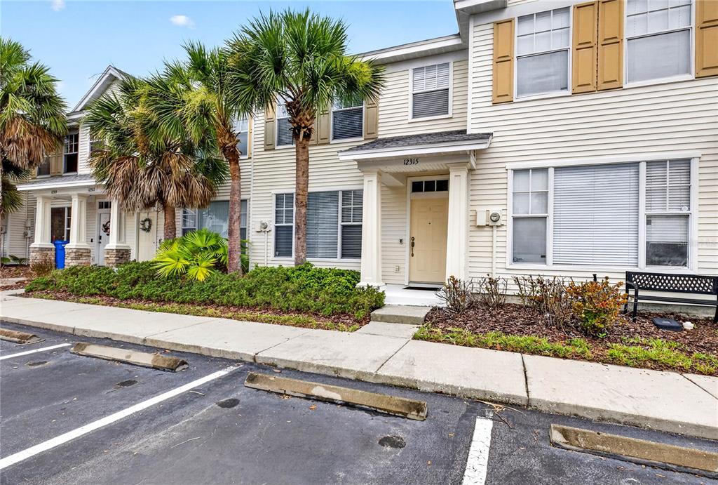 A two-story townhouse with light siding, a tan front door, and palm trees in front — 12315 COUNTRY WHITE CIRCLE, TAMPA, FL