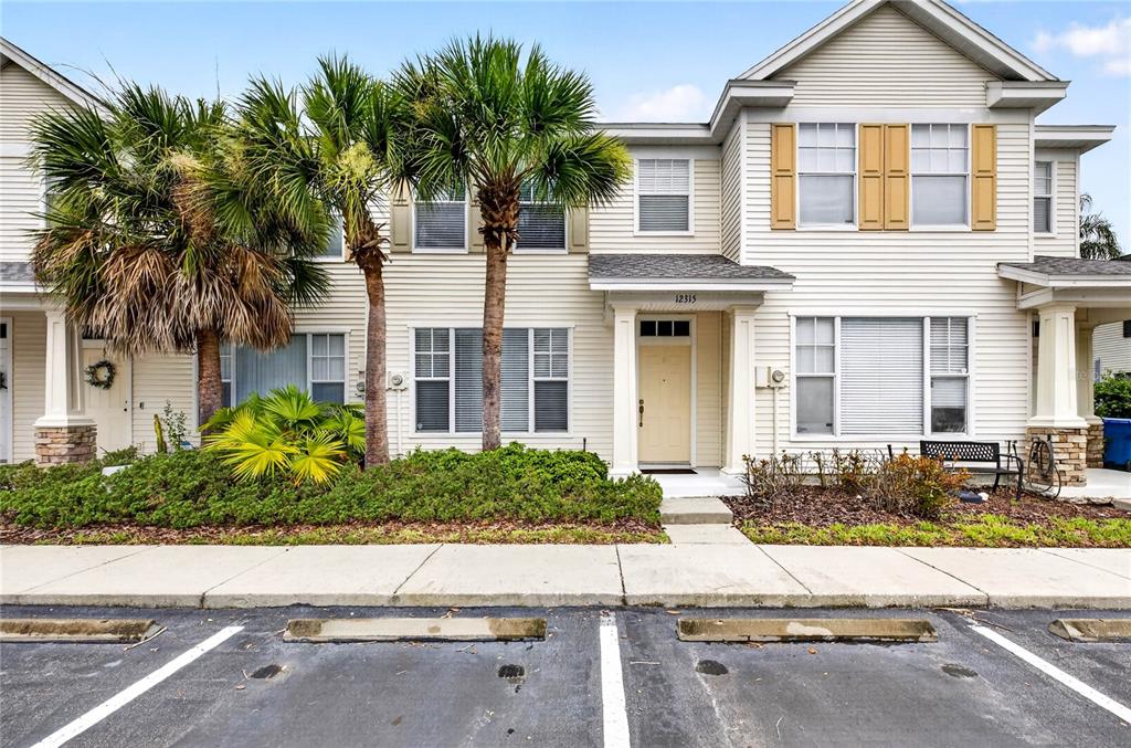 A two-story townhouse exterior features light siding, a covered entrance, and two palm trees — 12315 COUNTRY WHITE CIRCLE, TAMPA, FL