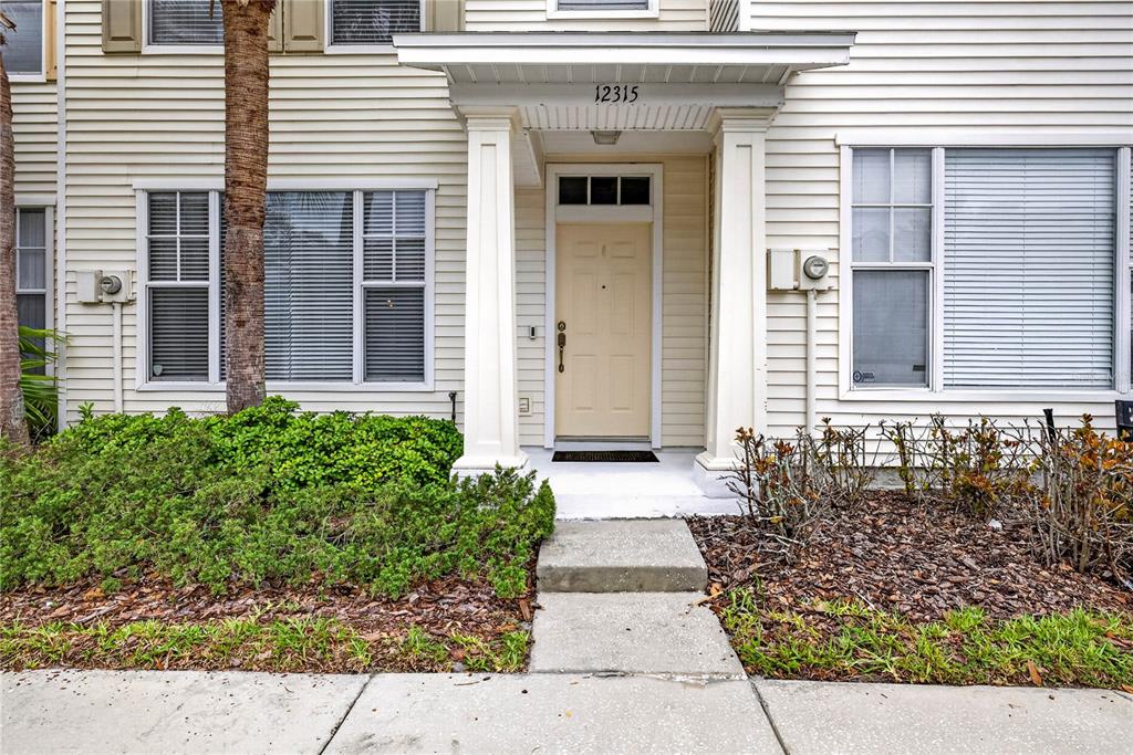 The exterior of a residential building features a beige door, white columns, and landscaping — 12315 COUNTRY WHITE CIRCLE, TAMPA, FL