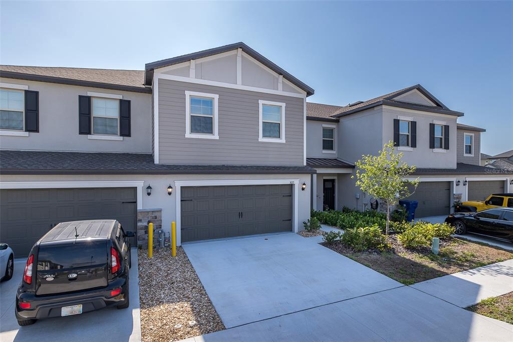 A two-story townhouse exterior features gray siding, a two-car garage, and a concrete driveway — 3072 HOVER HALL LANE, NEW PORT RICHEY, FL