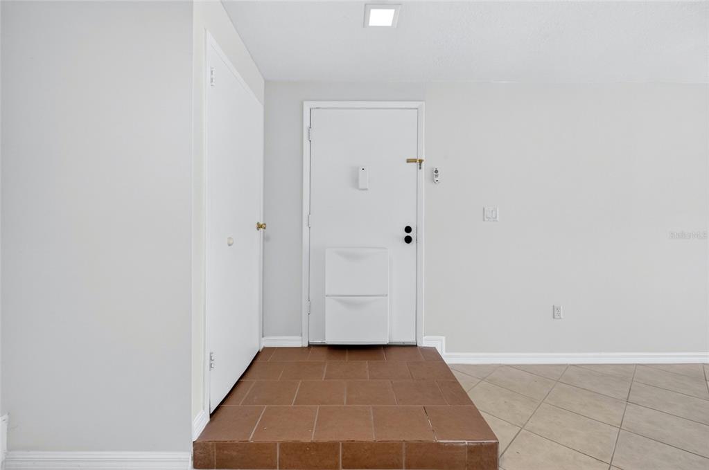 An entryway features a white door, a tiled landing, and a closet with a white door — 3272 S SEMORAN BOULEVARD UNIT 11, ORLANDO, FL