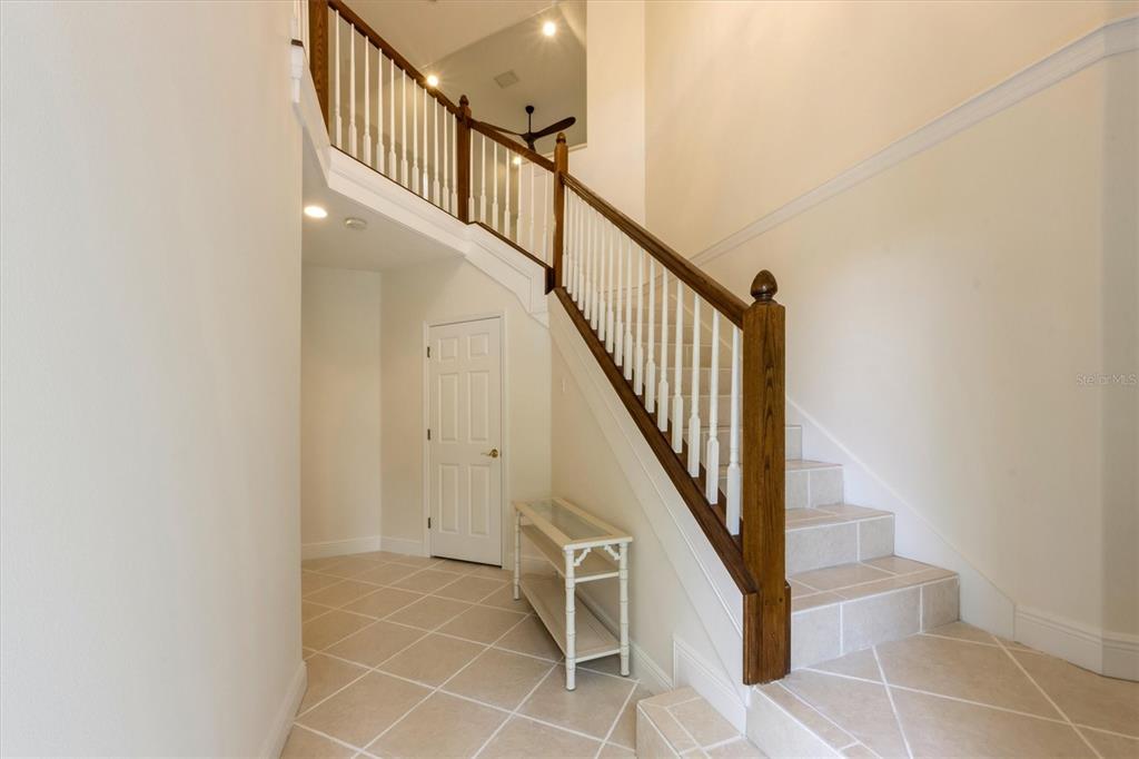 A foyer features a tiled floor, a white door, and a staircase with wooden railings — 4118 OSPREY HARBOUR LOOP UNIT 4118, CORTEZ, FL