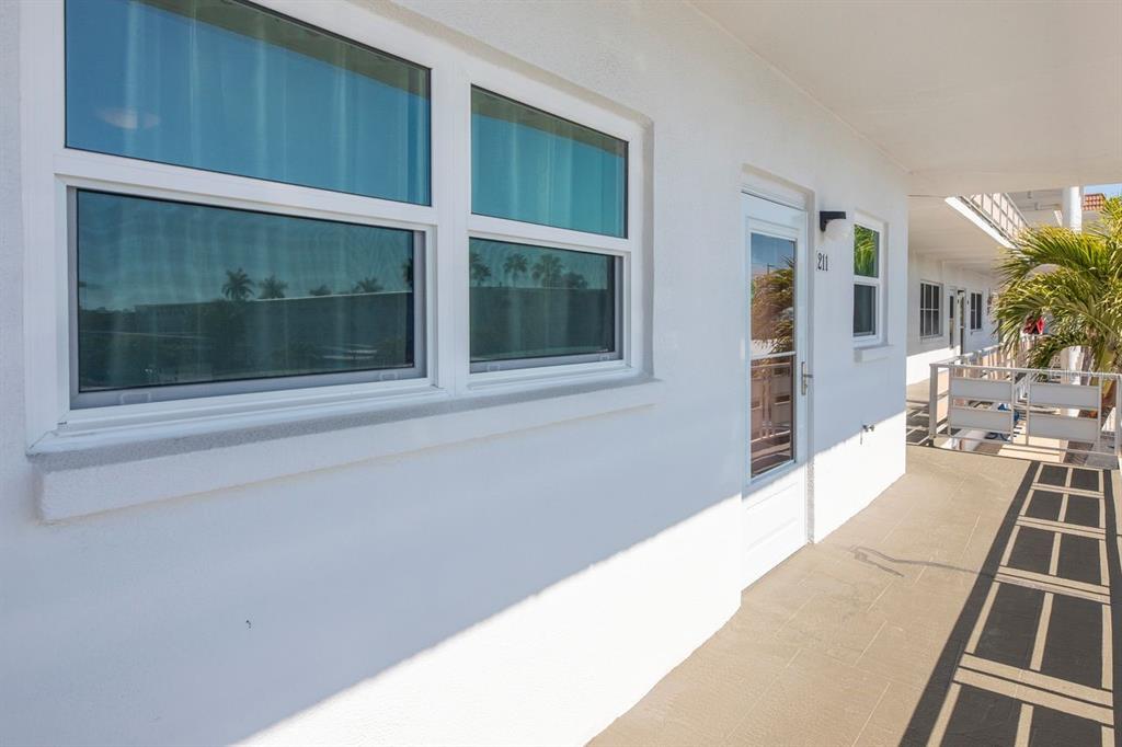 A white exterior wall features a double window and a door numbered 211 — 3128 59TH STREET S UNIT 211, GULFPORT, FL