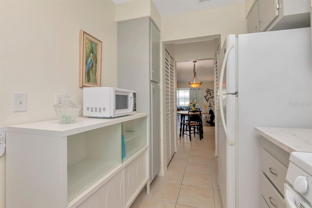 A kitchen features white cabinets, a microwave on a console table, and tiled flooring — 3128 59TH STREET S UNIT 211, GULFPORT, FL