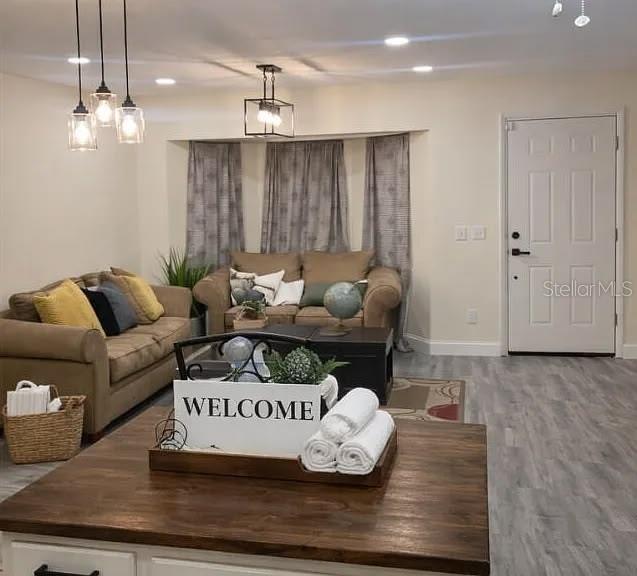 A living room features light-colored walls, gray wood-look flooring, two brown sofas, and pendant lighting — 1020 LEE AVENUE NW, PALM BAY, FL