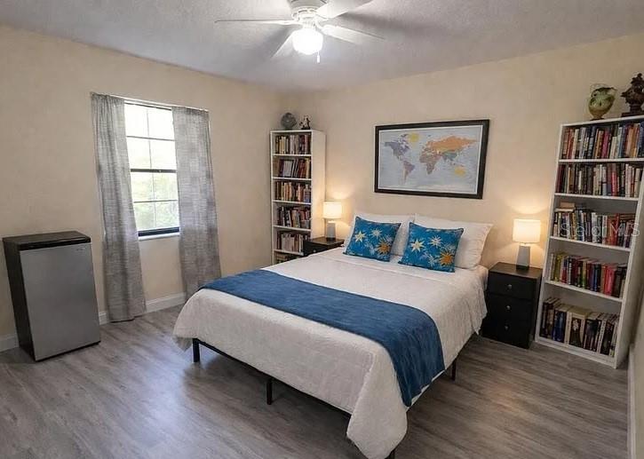 A bedroom features a bed, two bookshelves, a small refrigerator, and a world map — 1020 LEE AVENUE NW, PALM BAY, FL