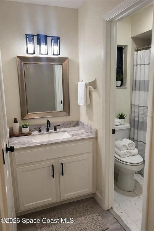 A bathroom features a vanity with a marble countertop, a mirror, and a toilet — 1020 LEE AVENUE NW, PALM BAY, FL