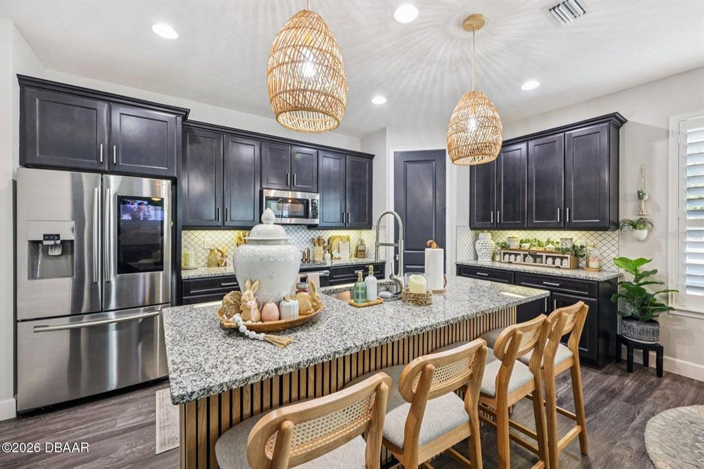 A kitchen features dark cabinets, granite countertops, a central island, and two woven pendant lights — 6827 FORKMEAD LANE, PORT ORANGE, FL