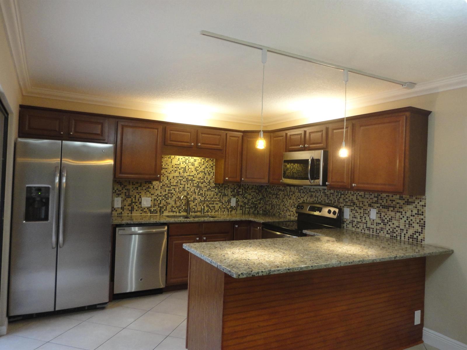 A kitchen with wood cabinets, granite countertops, stainless steel appliances, and a mosaic tile backsplash — 3008 San Clara Drive # b, Delray Beach FL 33445, DELRAY BEACH, FL