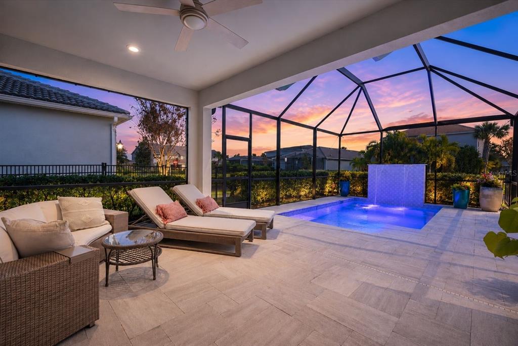 A covered patio features a pool with a water feature, lounge chairs, and outdoor seating — 11712 GOLDEN BAY PLACE, BRADENTON, FL
