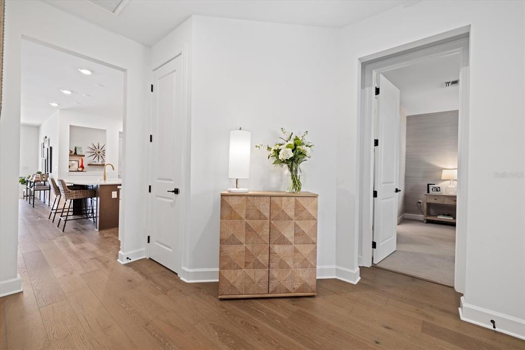 A hallway features light wood flooring, a textured wooden cabinet, and two open doorways — 11712 GOLDEN BAY PLACE, BRADENTON, FL