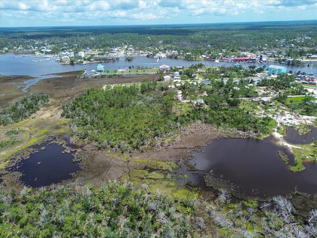 An aerial view shows a wooded lot adjacent to a pond and a coastal waterway — TBD SW 276 AVENUE, STEINHATCHEE, FL