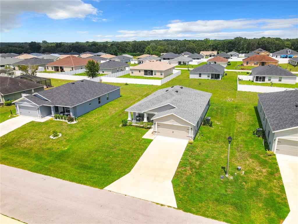 An aerial view shows several suburban single-family homes with driveways and lawns under a blue sky — 5541 SE 92ND STREET, OCALA, FL