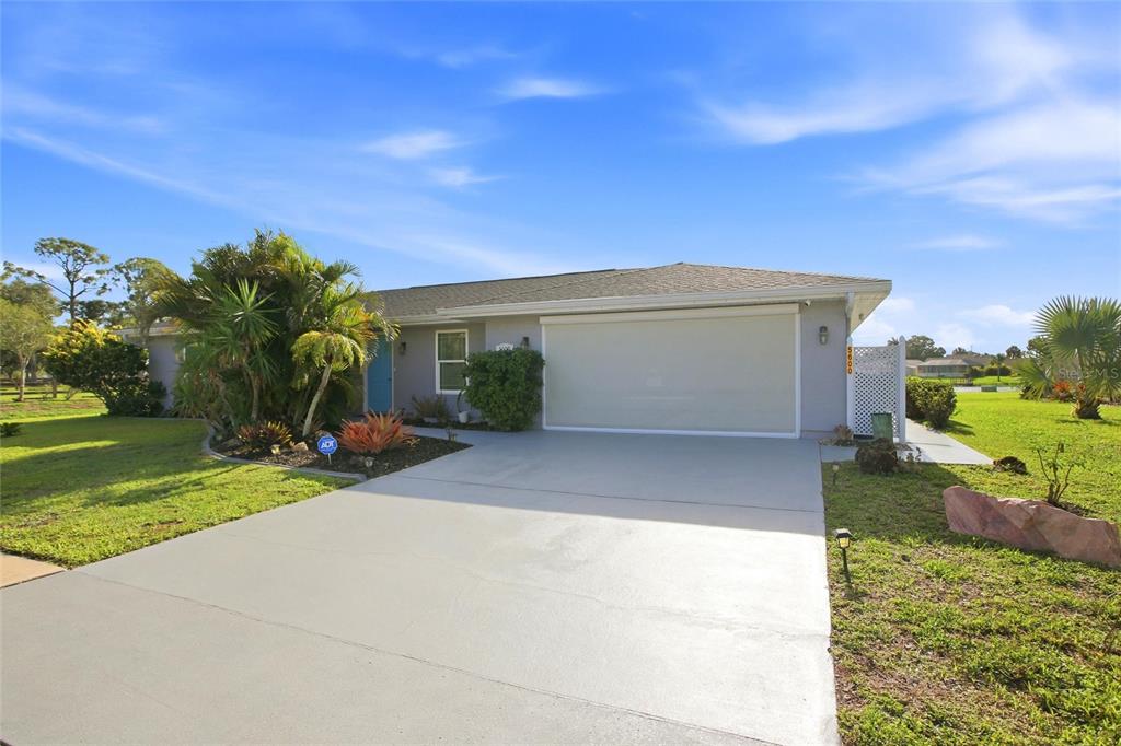 A single-story house with a gray exterior, a large driveway, and a covered garage entrance — 5600 LINGLE STREET, NORTH PORT, FL