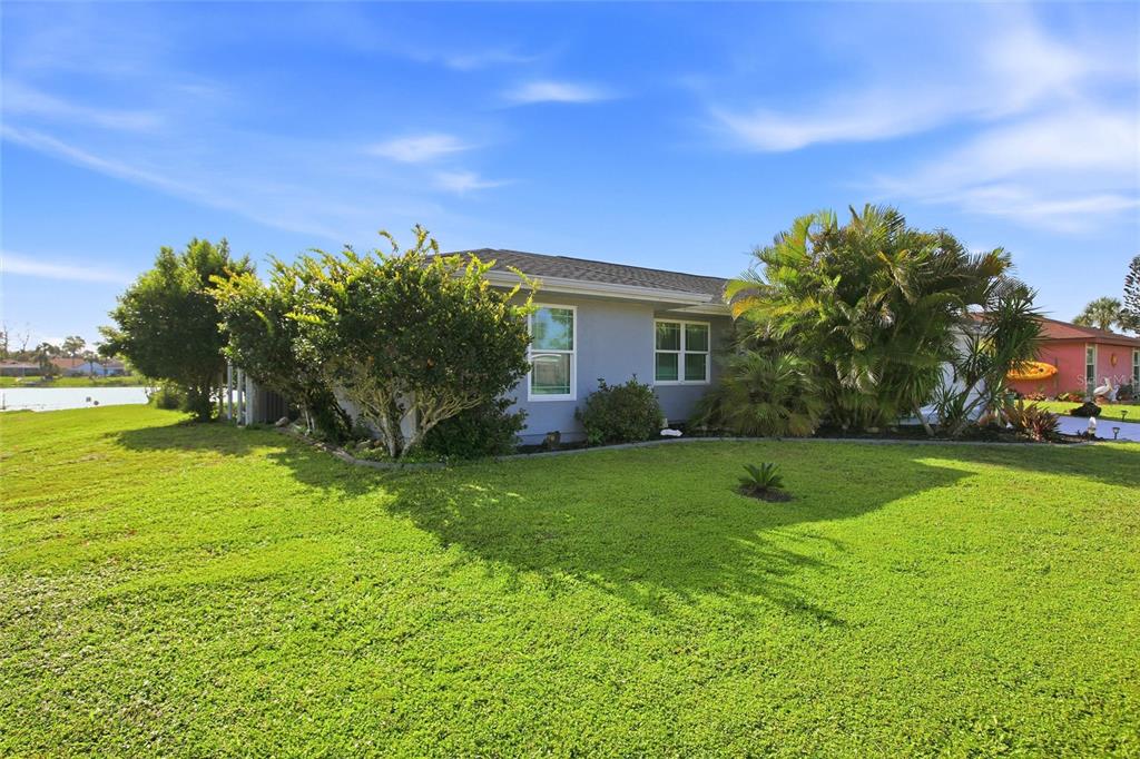 A single-story house with gray siding and a large green lawn beside a lake — 5600 LINGLE STREET, NORTH PORT, FL