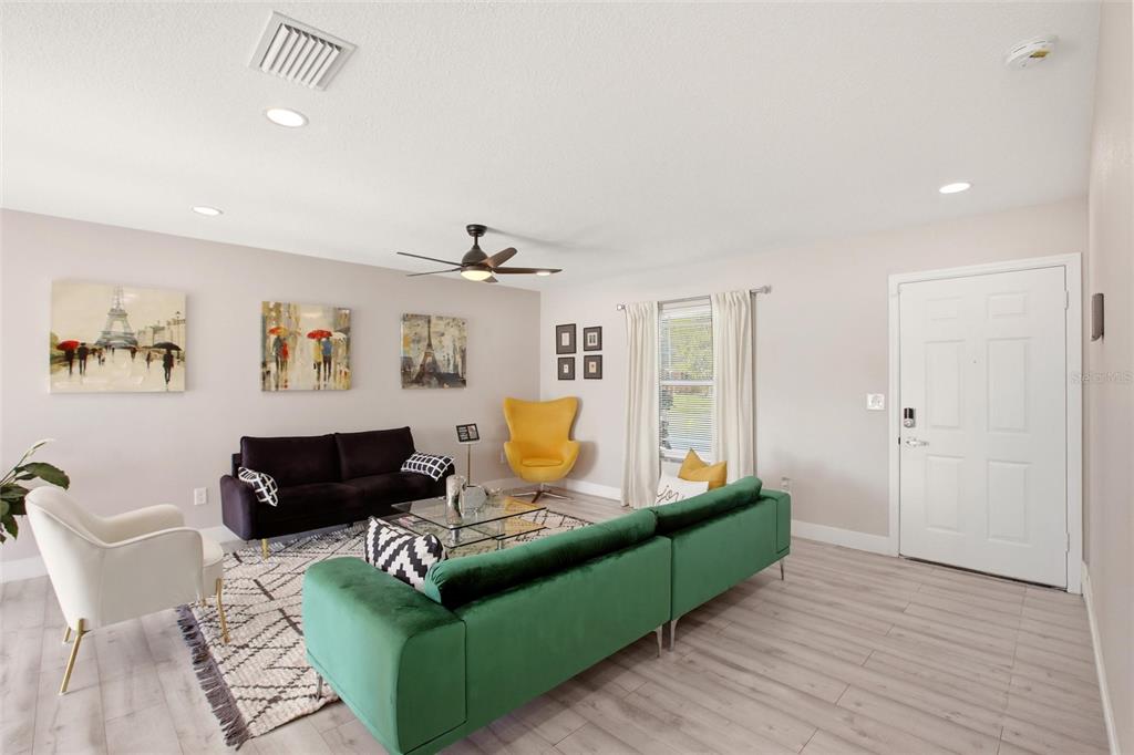 A living room features a green velvet sofa, a black sofa, and a yellow accent chair — 5600 LINGLE STREET, NORTH PORT, FL