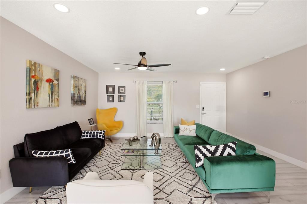 A living room features a black sofa, a green sofa, and a yellow accent chair — 5600 LINGLE STREET, NORTH PORT, FL