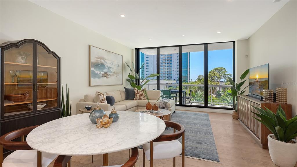 A living and dining area features a marble table, sectional sofa, and floor-to-ceiling windows — 300 S PINEAPPLE AVENUE UNIT 302, SARASOTA, FL